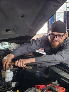 a man is working on an engine in his car while looking at the camera lens