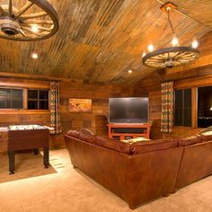 a living room filled with furniture and a flat screen tv on top of a wooden wall