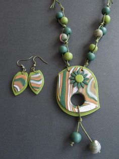 a necklace and earring set with green beads on a black surface, next to a pair of earrings