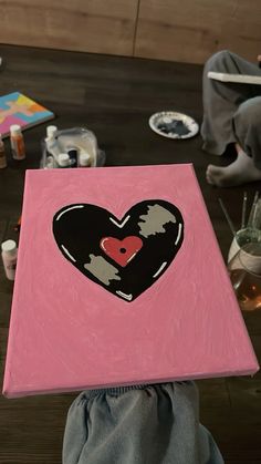 a person holding up a painting with a heart on it