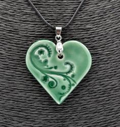 a green heart shaped pendant on a black cord