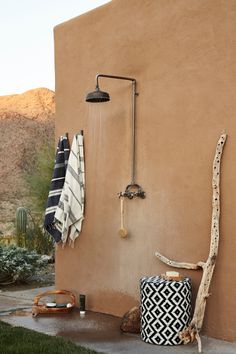 an outdoor shower with black and white towels hanging on the wall next to a cactus