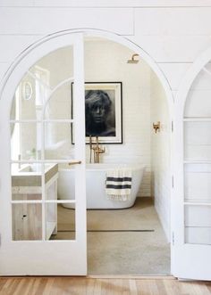 an arched doorway leading to a bathroom with a tub and sink