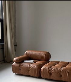 a brown leather couch sitting in front of a window