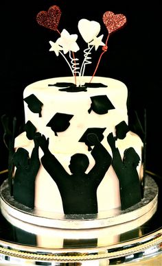 a cake decorated with black and white frosting, topped with silhouettes of people holding balloons