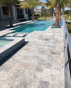 an outdoor swimming pool surrounded by palm trees and landscaping area with stone paversed walkway