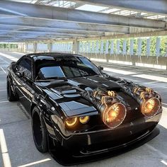 a black sports car with yellow lights on it's headlamps in a parking lot