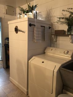 a white washer and dryer sitting in a room next to a door with plants on it