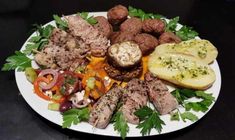 a white plate topped with meat and veggies on top of a black table