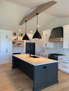 a kitchen with an island and two pendant lights hanging over it's counter tops