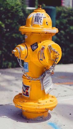 a yellow fire hydrant with stickers on it