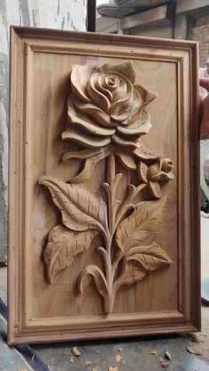 a wooden carving of a rose with leaves on it's back and the petals still attached to the frame