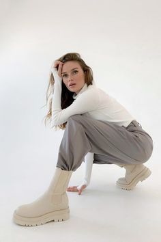 a woman in white shirt and grey pants kneeling on the ground with her hand on her head