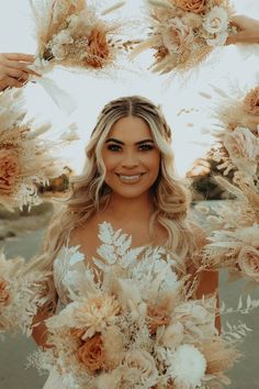 a woman holding flowers in front of her face and smiling at the camera, surrounded by feathers