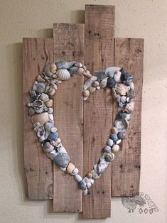 a heart made out of seashells is mounted on a wooden pallet wall