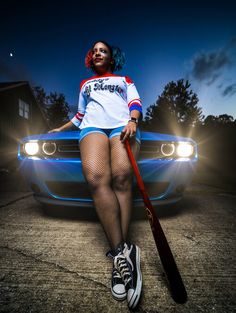 a woman in fishnet stockings holding a baseball bat next to a blue sports car