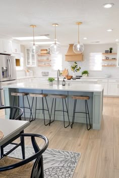 a kitchen with white cabinets and blue counter tops, an island in between two chairs