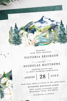 an image of a wedding card with watercolor flowers and mountains in the back ground