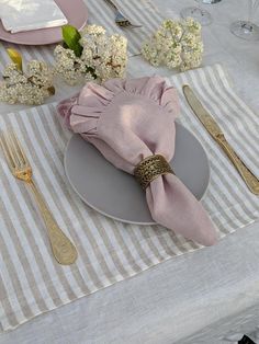 a table set with silverware, napkins and flowers