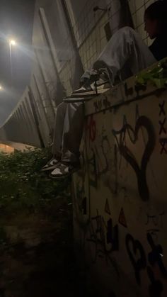 a man sitting on top of a cement wall under a street light in the dark