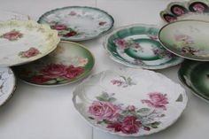 many plates are sitting on the table with flowers painted on them and one is empty