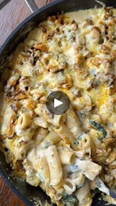 a skillet filled with macaroni and cheese on top of a wooden table