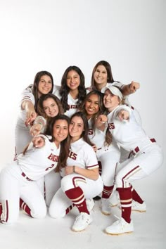 a group of women in white baseball uniforms posing for a photo