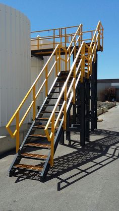 a set of yellow stairs next to a white building with a metal railing on it