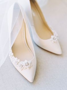 the bride's wedding shoes are adorned with flowers and pearls, along with a veil