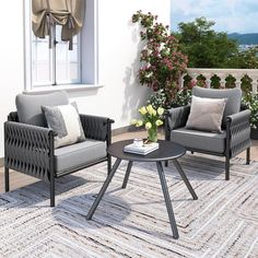 two chairs and a coffee table on a rug in front of a window with flowers