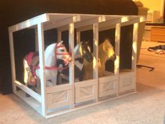 three toy horses are in a small cage