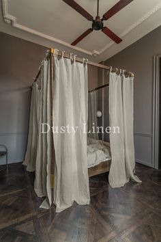 a canopy bed with curtains hanging from it's sides in a room that has wood floors