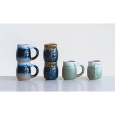 three coffee mugs sitting next to each other on a white counter top, one is blue and the other is green