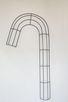 a metal sculpture with a curved design on it's side, against a white wall