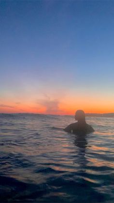 a person swimming in the ocean at sunset