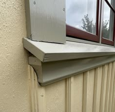 an open window on the side of a building next to a metal gutter door