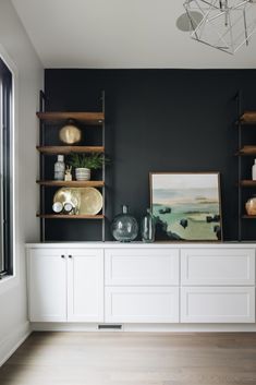 a room that has some shelves on the wall with pictures and vases in it