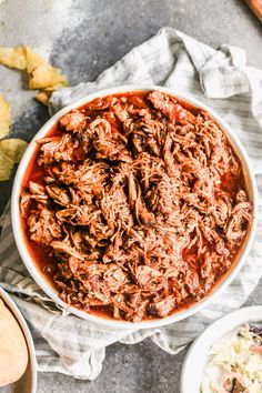 shredded meat in a white bowl next to two bowls of potato chips