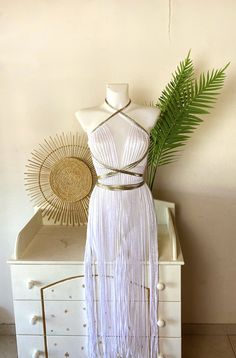 a white dress on display next to a plant