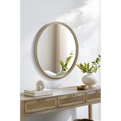 a mirror sitting on top of a wooden table next to a vase and potted plant