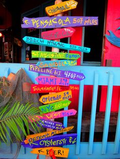 colorful wooden signs are on the side of a blue fence in front of a building