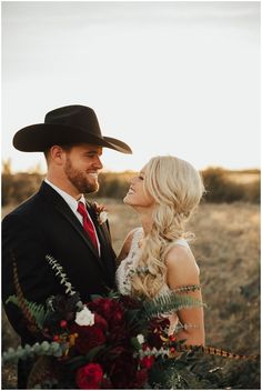 a man in a cowboy hat holding a bouquet of flowers and smiling at the camera