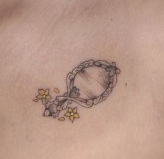 a woman's stomach with a small tattoo on the side of her belly and flowers around it