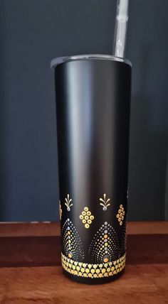 a black and gold cup sitting on top of a wooden table