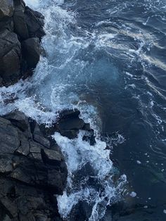 the water is splashing on the rocks near the shore