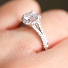 a close up view of a diamond ring on someone's finger, with the center stone set in white gold