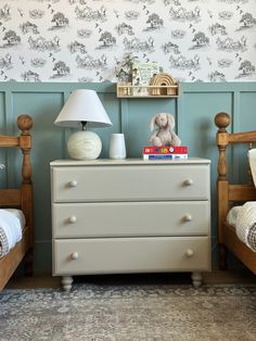 a bedroom with two twin beds and a lamp on top of the dresser next to each other