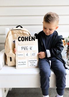 a young boy sitting on a bench holding a sign