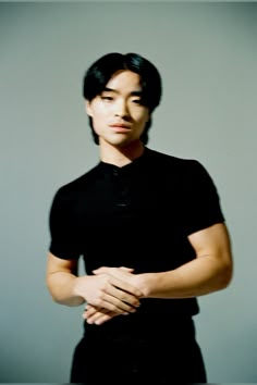 a man standing with his arms crossed and looking at the camera while wearing a black shirt