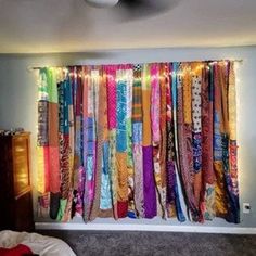 a bed room with a large window covered in colorful scarves and fairy lights hanging from the ceiling